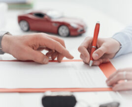 A person signing their business auto insurance policy with their insurance agent.